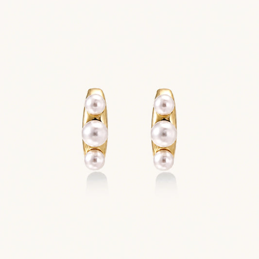 14K gold-plated curved stud earrings with three white freshwater pearls aligned vertically on cream background