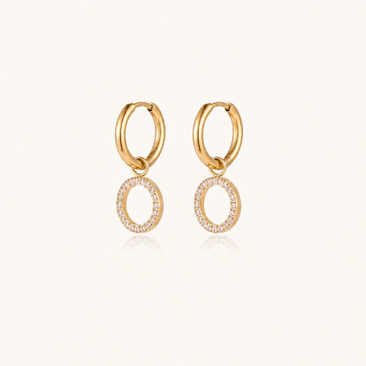Gold-plated huggie hoop earrings with CZ-studded open circle charms on beige background