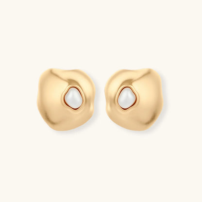 Gold organic-shaped stud earrings with white pearl centers and flowing curves on neutral background.