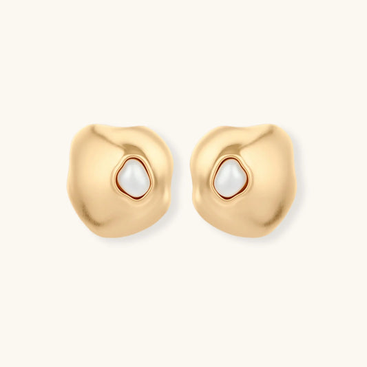 Gold organic-shaped stud earrings with white pearl centers and flowing curves on neutral background.