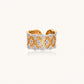 Two-tone gold and silver lattice ring with clover pattern and crystal accents on white background