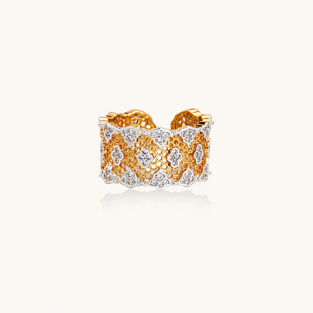 Two-tone gold and silver lattice ring with clover pattern and crystal accents on white background