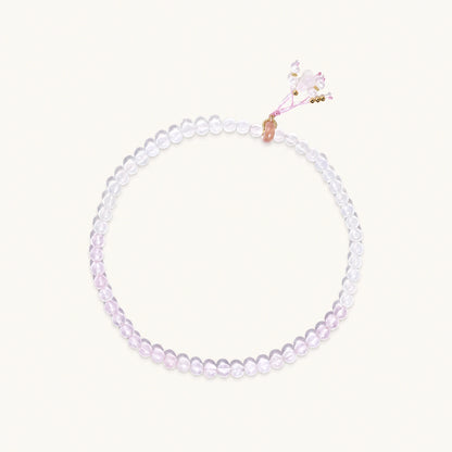 Double-wrap lavender beaded bracelet with rose quartz, pearls, gold vermeil charm and pink tassel on white background.