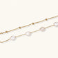 Double-strand gold bracelet with irregular baroque pearls and smooth freshwater pearls on cream background.