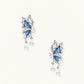 Silver butterfly earrings with blue denim fabric wings and dangling teardrop crystals on cream background
