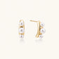 14K gold-plated curved stud earrings with three white freshwater pearls aligned vertically on cream background