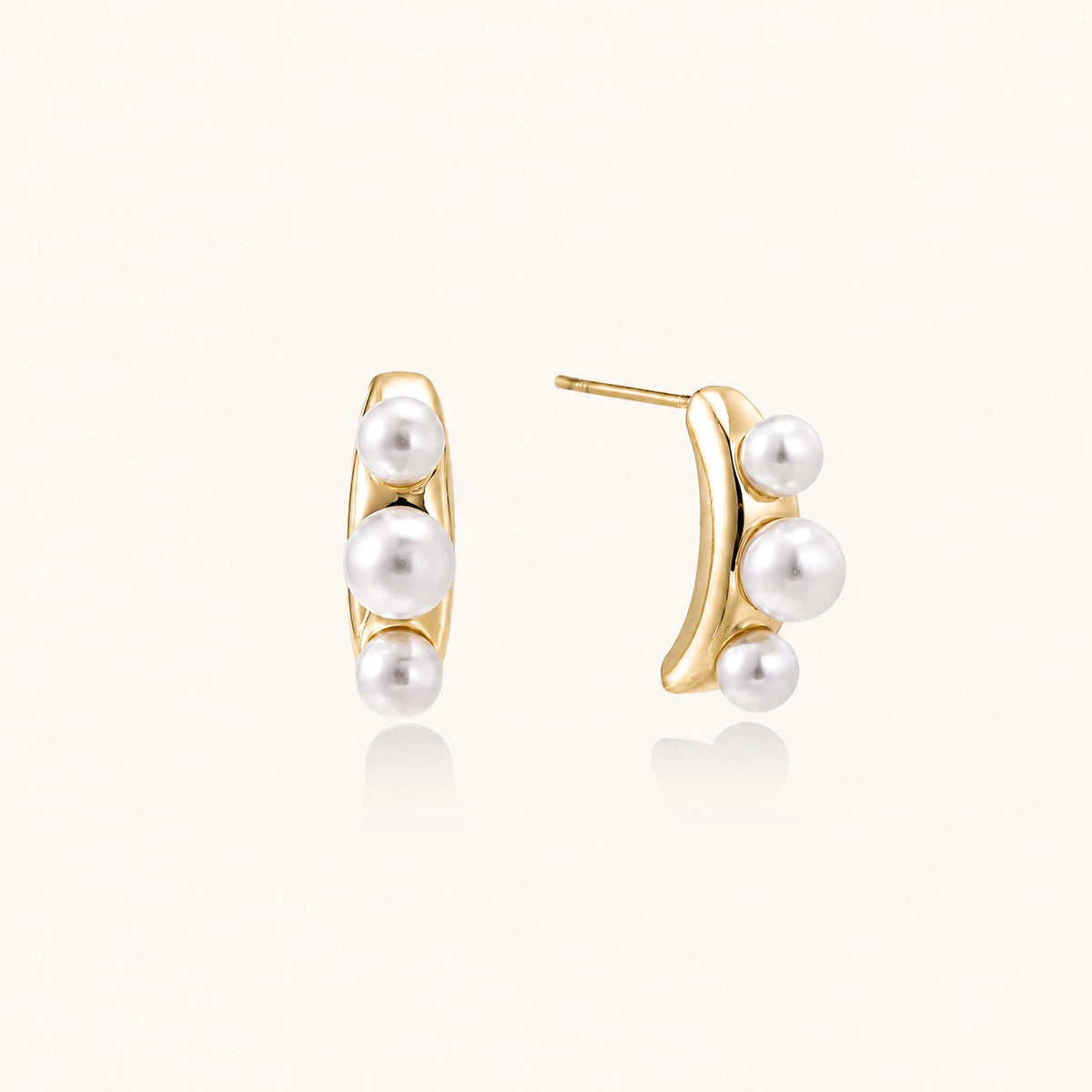 14K gold-plated curved stud earrings with three white freshwater pearls aligned vertically on cream background
