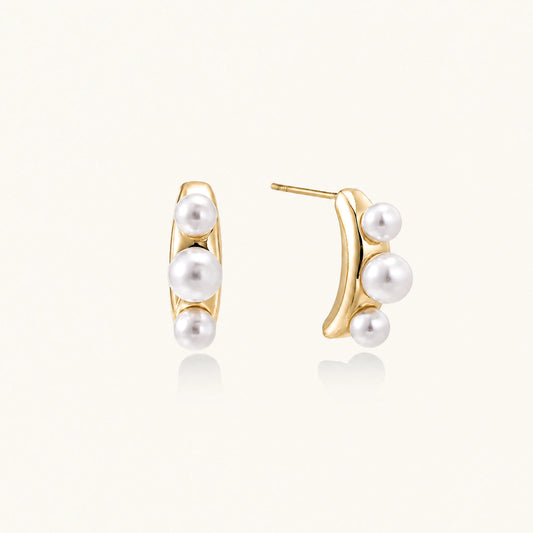 14K gold-plated curved stud earrings with three white freshwater pearls aligned vertically on cream background