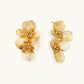 Pair of gold-plated double flower earrings with textured petals and crystal centers on cream background.