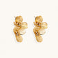 Pair of gold-plated double flower earrings with textured petals and crystal centers on cream background.