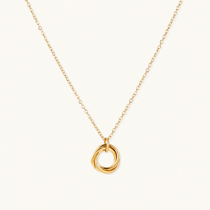 Delicate gold-plated necklace with three interlocking circle rings forming a minimalist knot pendant on cream background