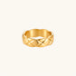 Close-up of an 18K gold-plated twisted band ring with dimensional braided pattern on cream background.