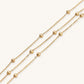 Three-strand gold-plated bracelet with clustered ball beads and adjustable clasp on cream background