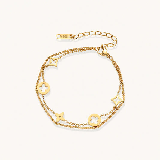 Double-layer gold-plated bracelet with quatrefoil and star charms on cream background, 18K gold finish.