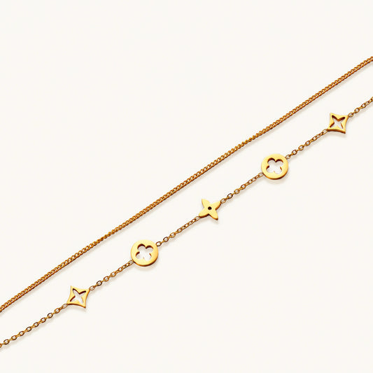 Double-layer gold-plated bracelet with quatrefoil and star charms on cream background, 18K gold finish.