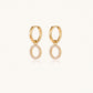 Gold-plated huggie hoop earrings with CZ-studded open circle charms on beige background