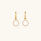 Gold-plated huggie hoop earrings with CZ-studded open circle charms on beige background