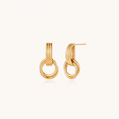 Gold stud earrings with vertical ridged bar connecting to triple interlocking circular rings on white background