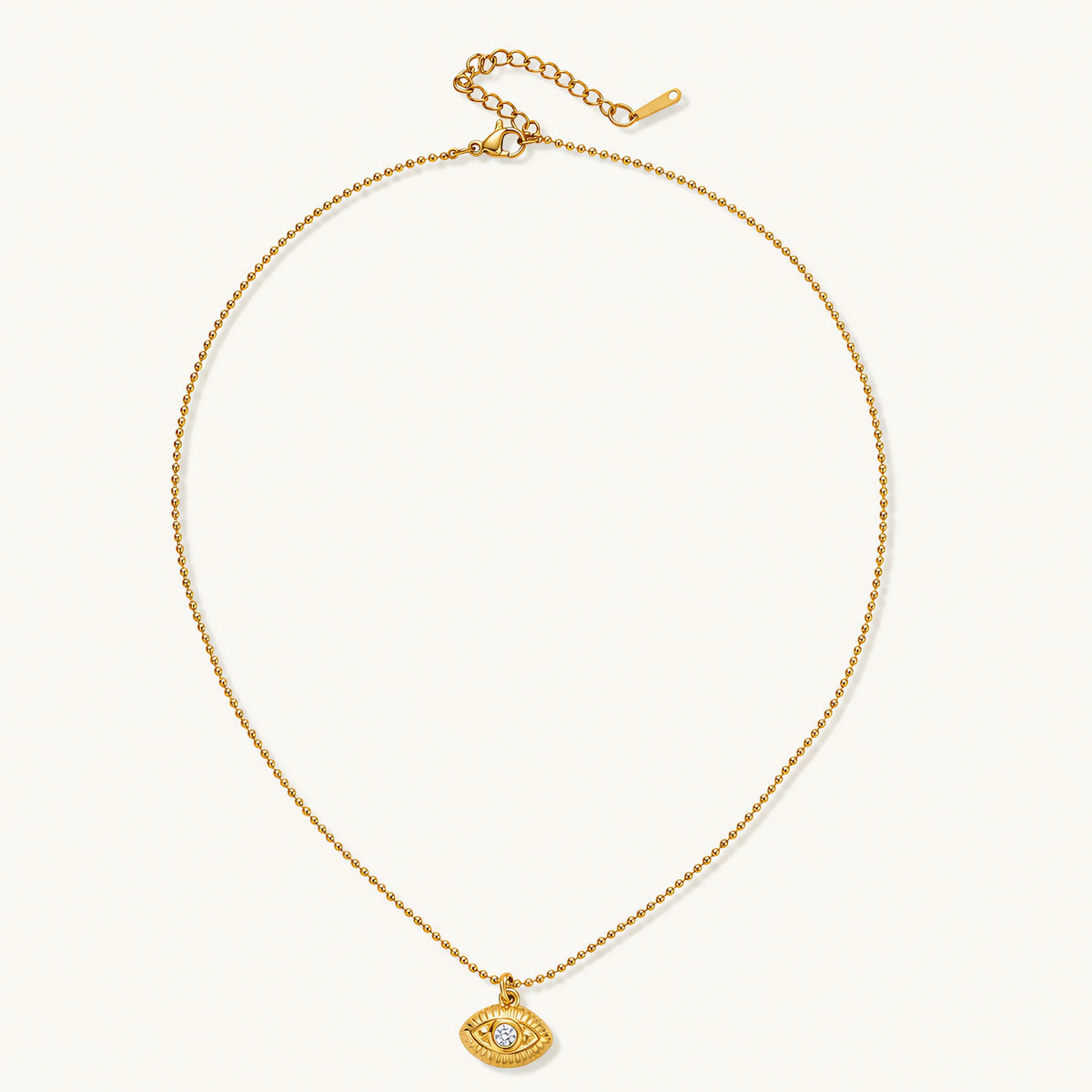 Layered necklace with green stone beads, gold spacers, white accents, and protective eye pendant on cream background.