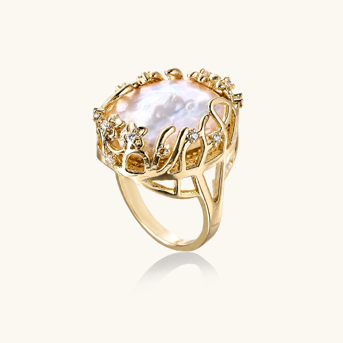 Gold filigree crown ring cradling an iridescent baroque freshwater pearl with crystal accents on white background