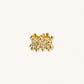 Gold-plated brass ring with sculptural petal-like elements in a wide band design on beige background