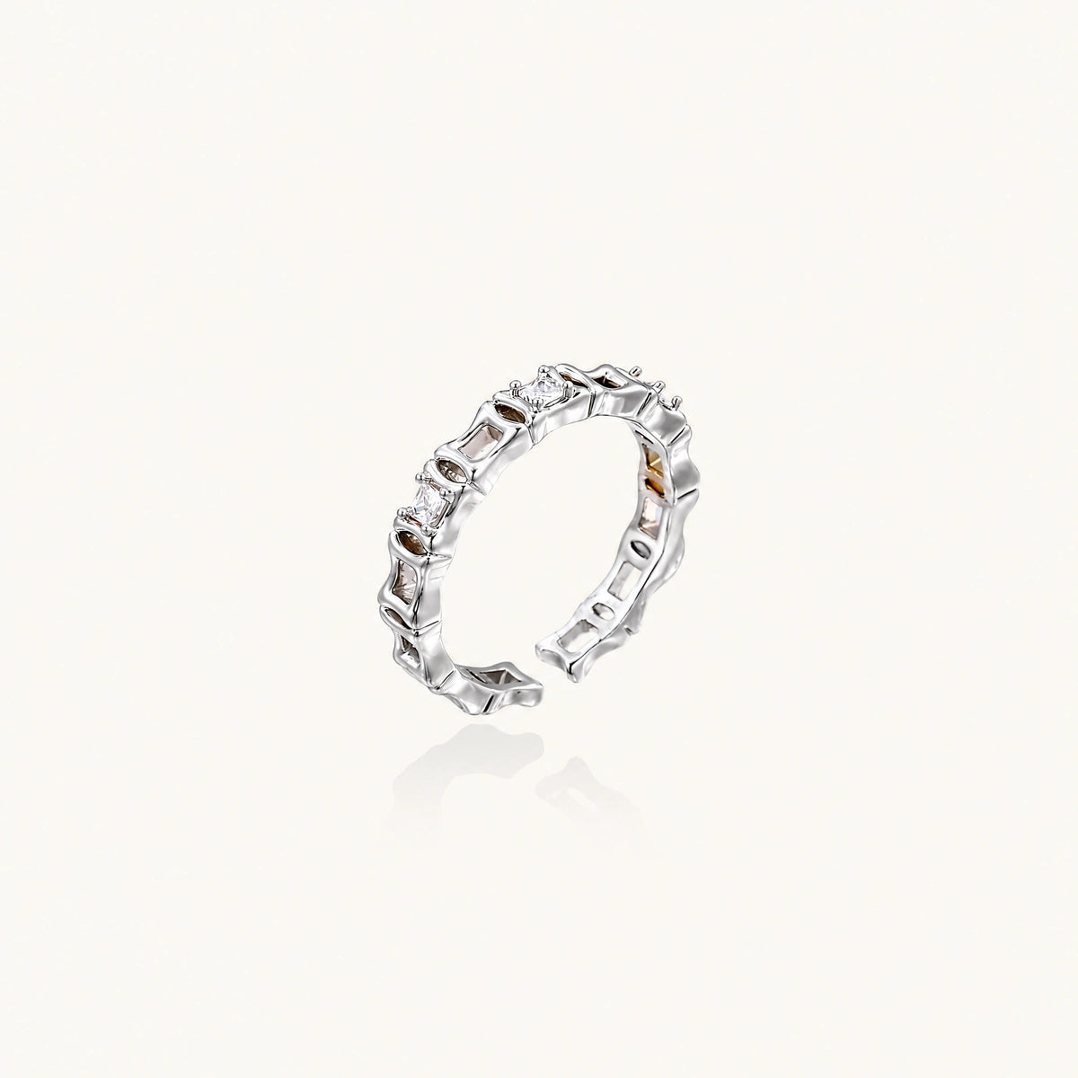 White gold plated ring with architectural lattice design and zirconia accents on cream background