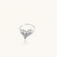 Silver ring with 3D heart formed by textured feather-like elements, white gold plated eco-brass on neutral background.