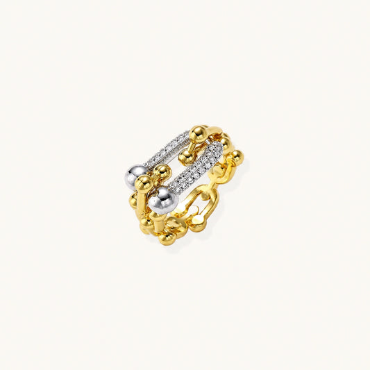 Triple-band gold ring with spherical bead chains and two crystal-pavé bars on cream background