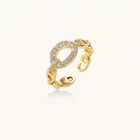 Gold-plated brass chain link ring with one oval CZ-pavé segment on cream background, adjustable cuff style.