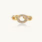 Gold-plated brass chain link ring with one oval CZ-pavé segment on cream background, adjustable cuff style.