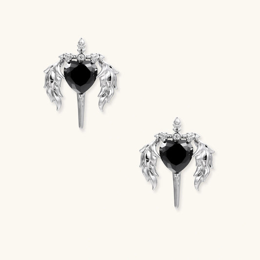 Silver drop earrings with twisted hoops and angel wings embracing black heart locket on white background.