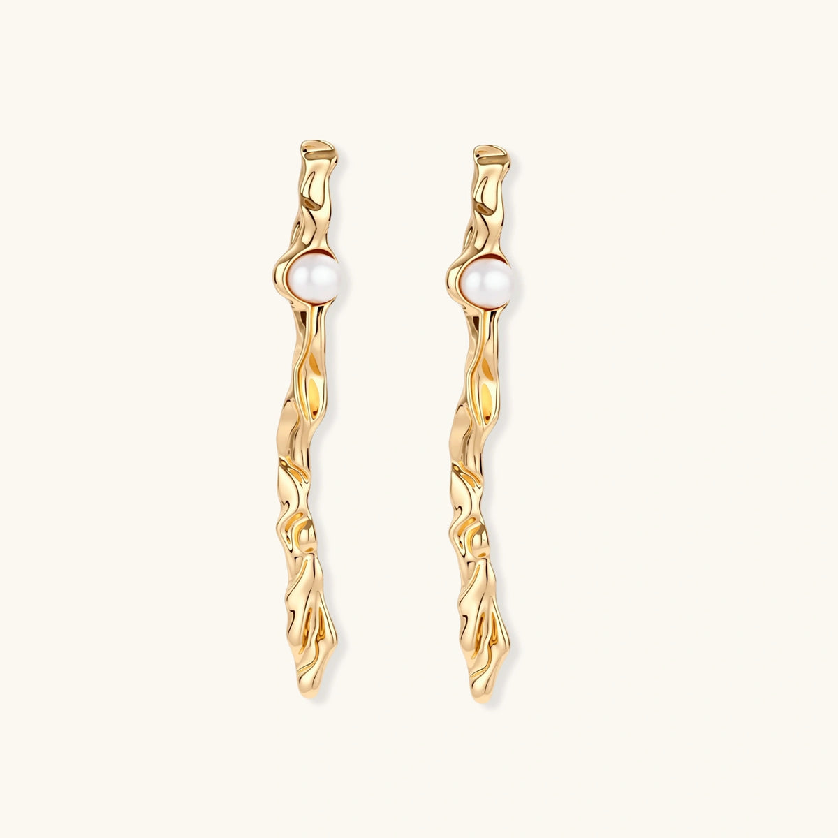 Long gold twisted sculptural earrings with round pearls, featuring flowing organic design on cream background