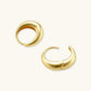 Chunky gold-plated sterling silver huggie hoop earrings with hinged closure mechanism on cream background.